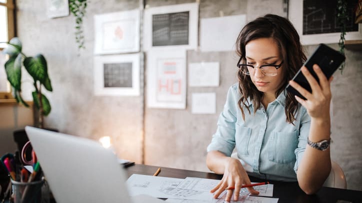 A woman sitting at a desk with a laptop and papers.