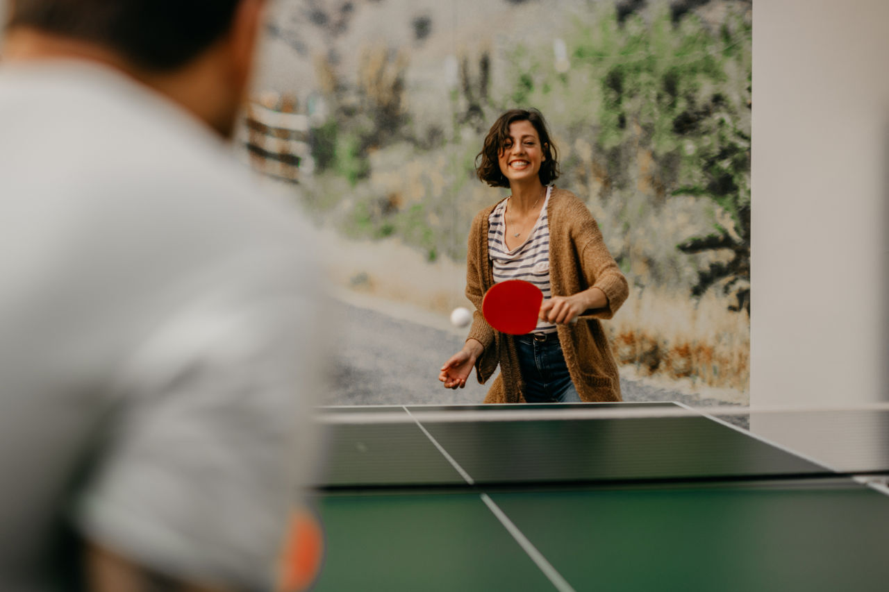 A young woman playing table tennis at work.