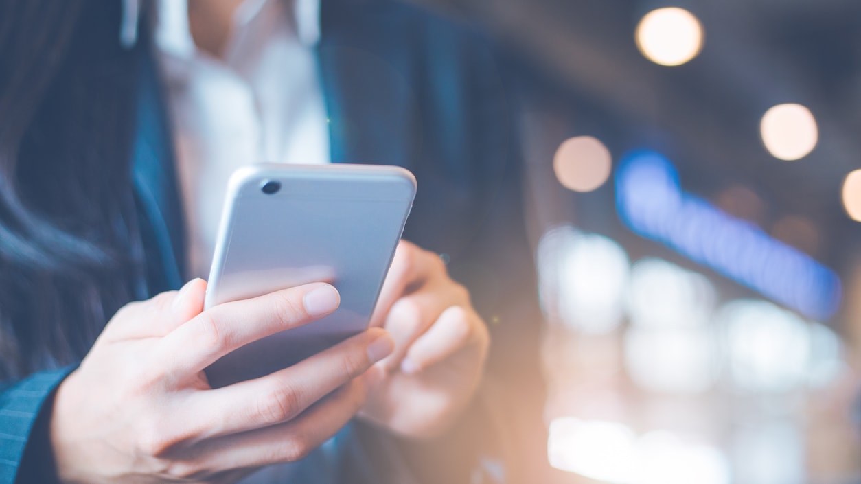 A woman is holding a cell phone in her hand.