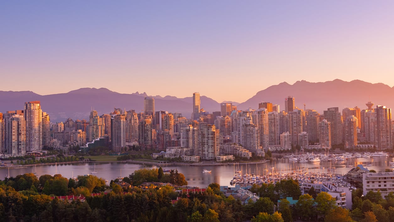 The city of vancouver at sunset with mountains in the background.