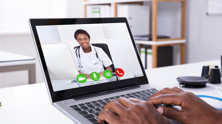 A man on a laptop using a video call with a doctor.