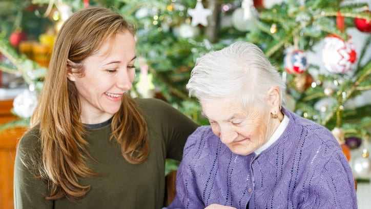 A woman is helping an elderly woman with a cookie.