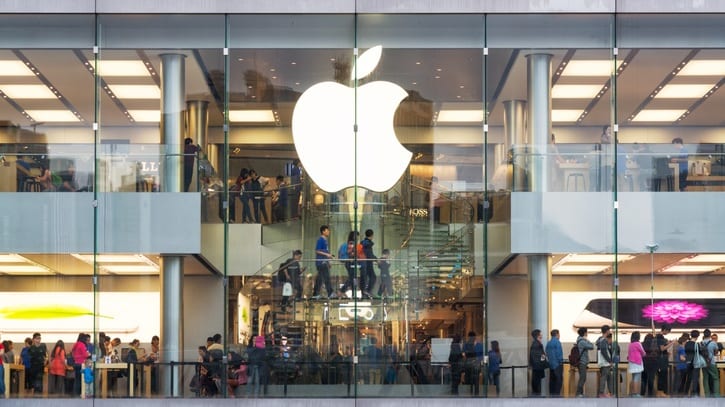 A group of people standing in front of an apple store.