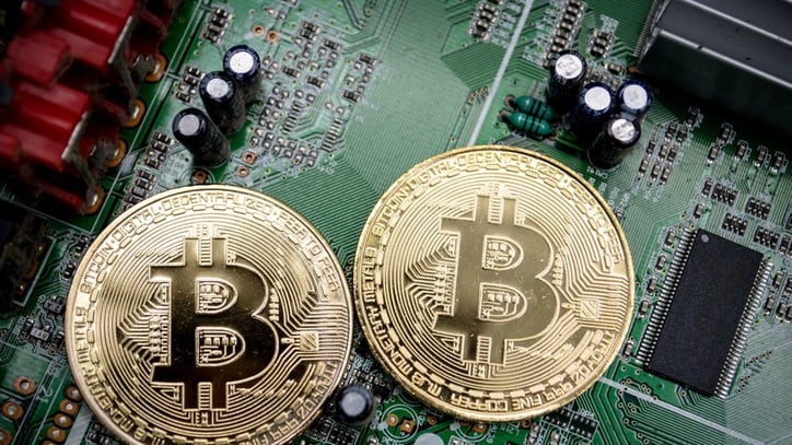 Two bitcoins sit on top of a circuit board.