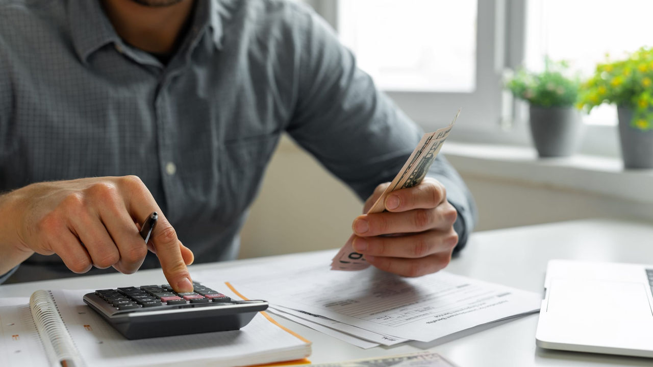 A man is using a calculator to do his taxes.