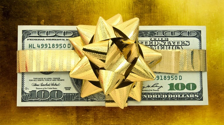 A gold bow tied around a dollar bill on a gold background.