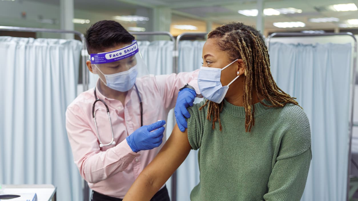 A man is giving a woman a vaccine in a hospital.