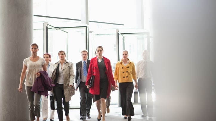 A group of business people walking through a glass door.