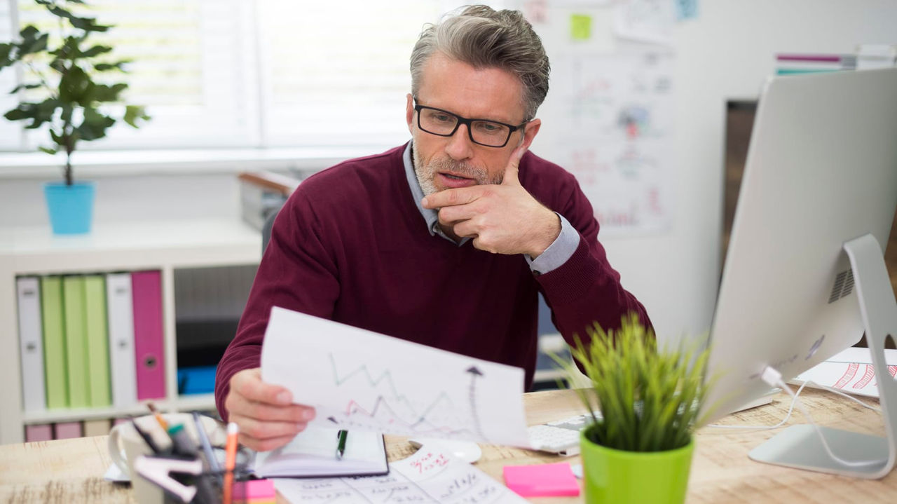 A man sitting at a desk looking at a graph.