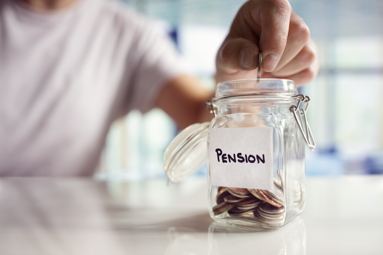Closeup of a hand putting money into a jar labeled "pension"