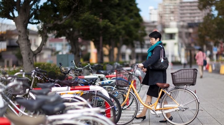 A woman standing next to a row of bicycles.
