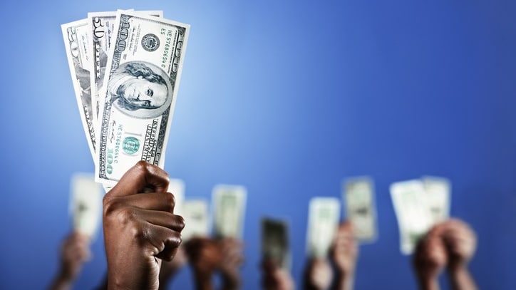 A group of people holding up dollar bills in front of a blue background.
