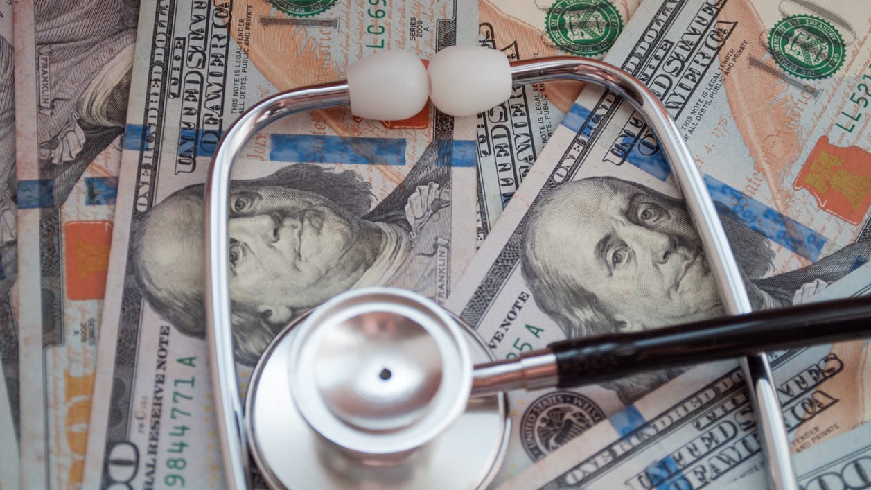 A stethoscope on top of a pile of money.