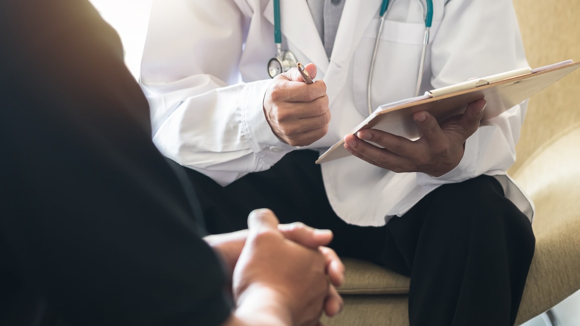 A doctor is talking to a patient in a chair.