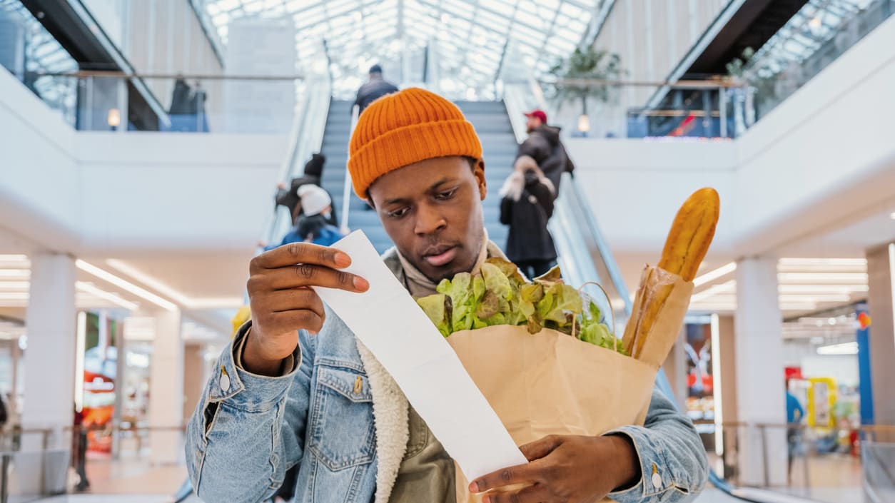 A man holding a bag of groceries in an escalator.