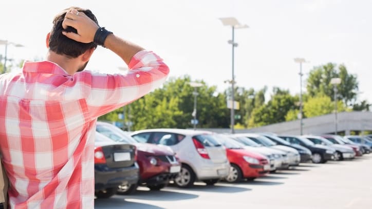 A man looking at cars in a parking lot.