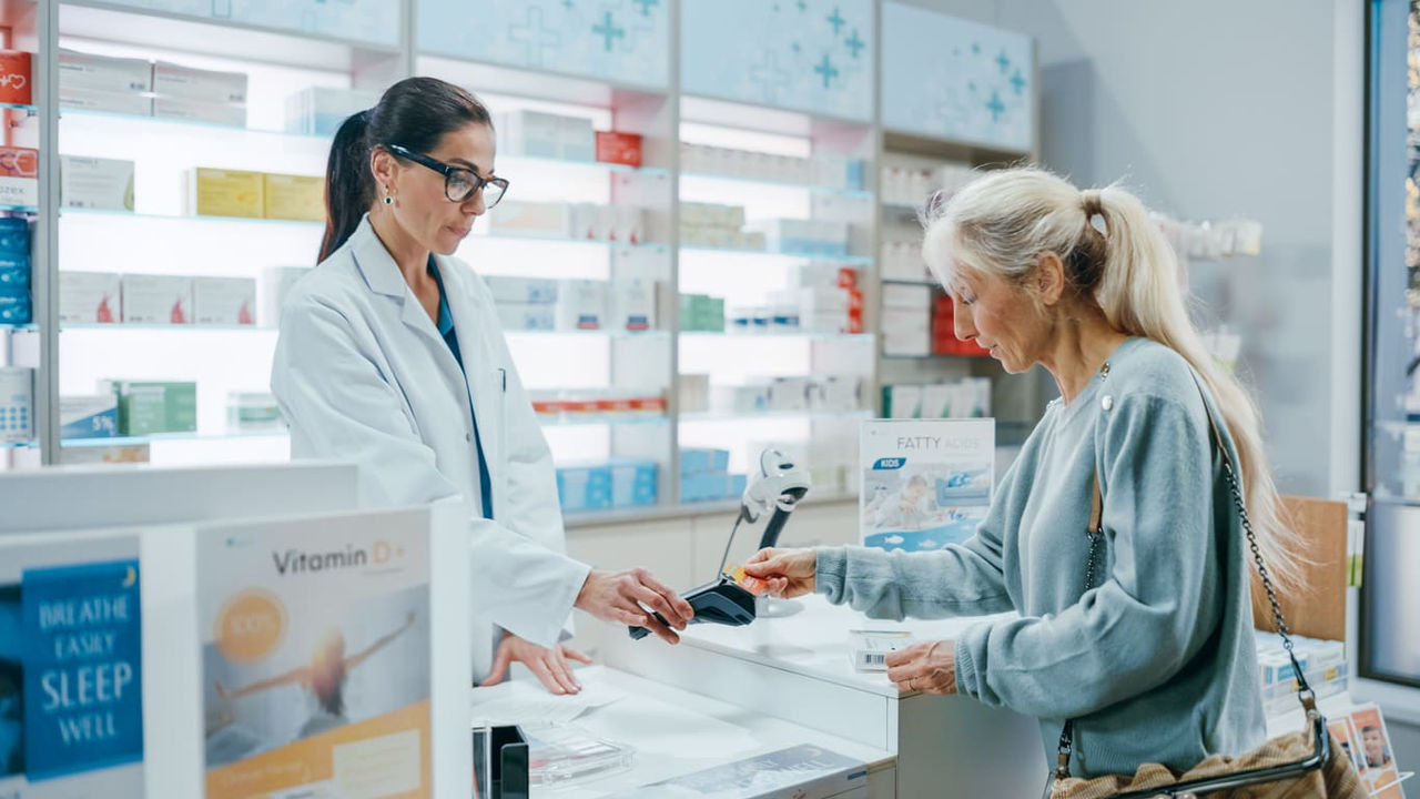 A woman is buying medicine from a pharmacist in a pharmacy.