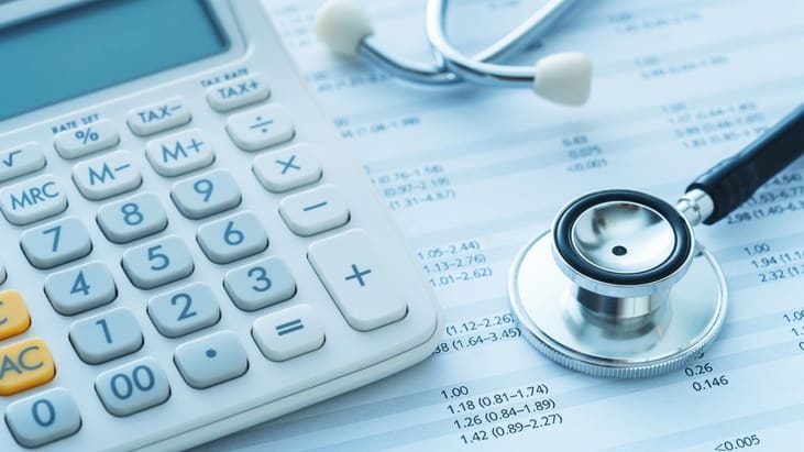 A stethoscope and a calculator on top of a sheet of paper.