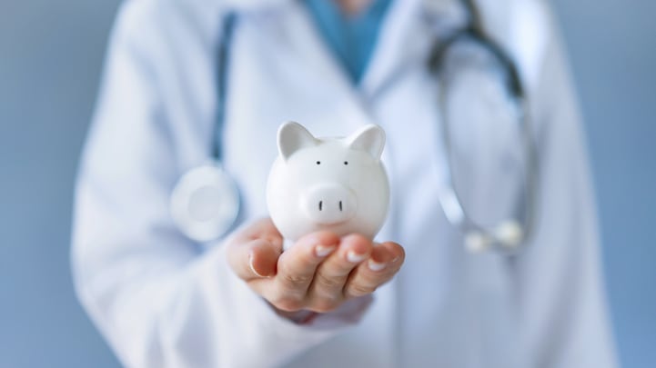 A female doctor holding a piggy bank.