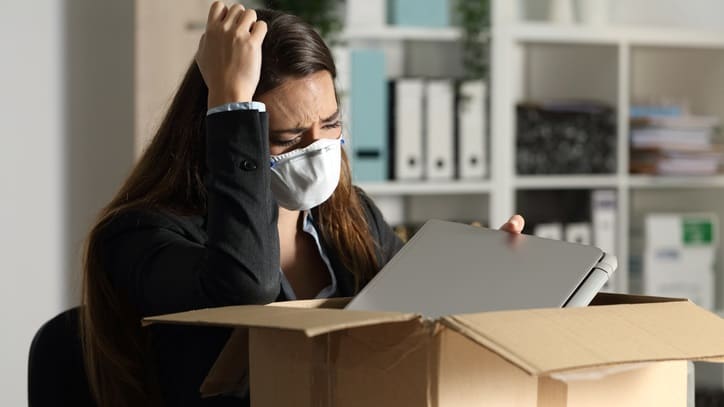 A woman wearing a face mask in front of a cardboard box.