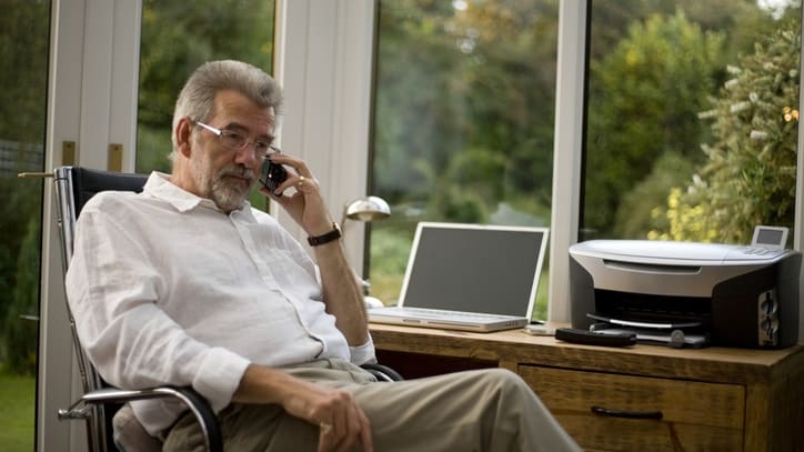 A man sitting in a chair and talking on the phone.