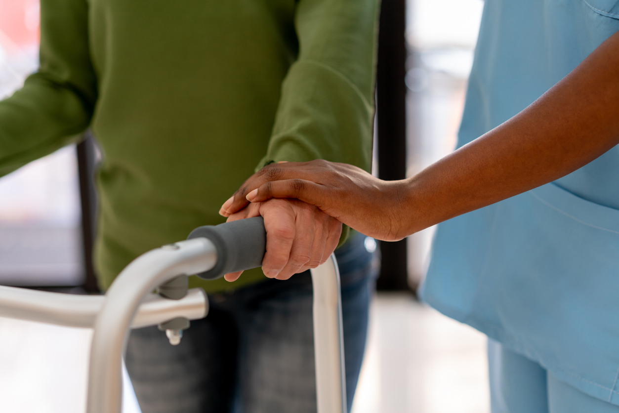 closeup of someone walking with a walker and the assistance of a medical professional