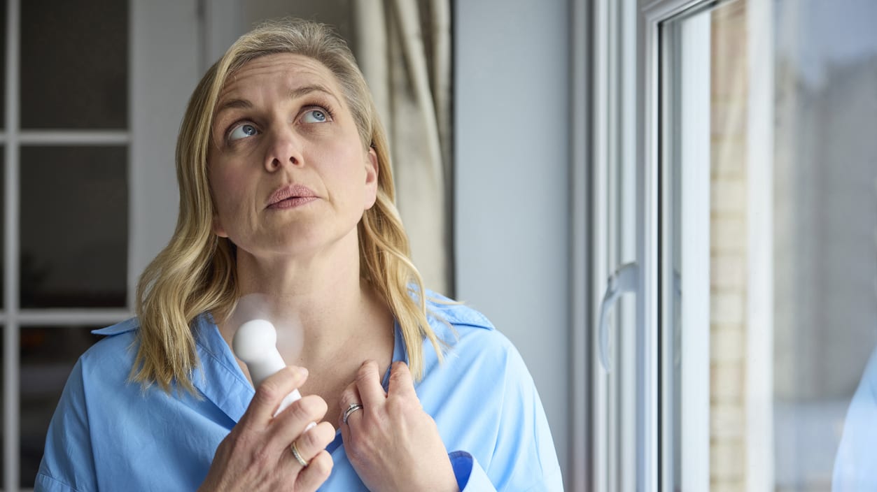 A woman holding a fan to help cool off