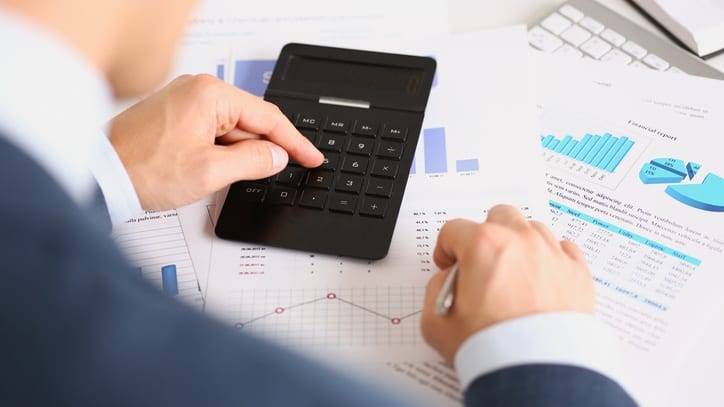 A businessman is using a calculator at his desk.