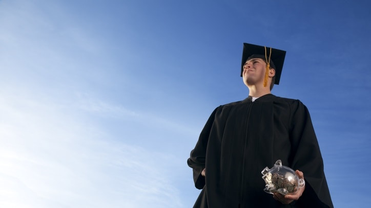 A young man in a graduation gown holding a graduation ball.