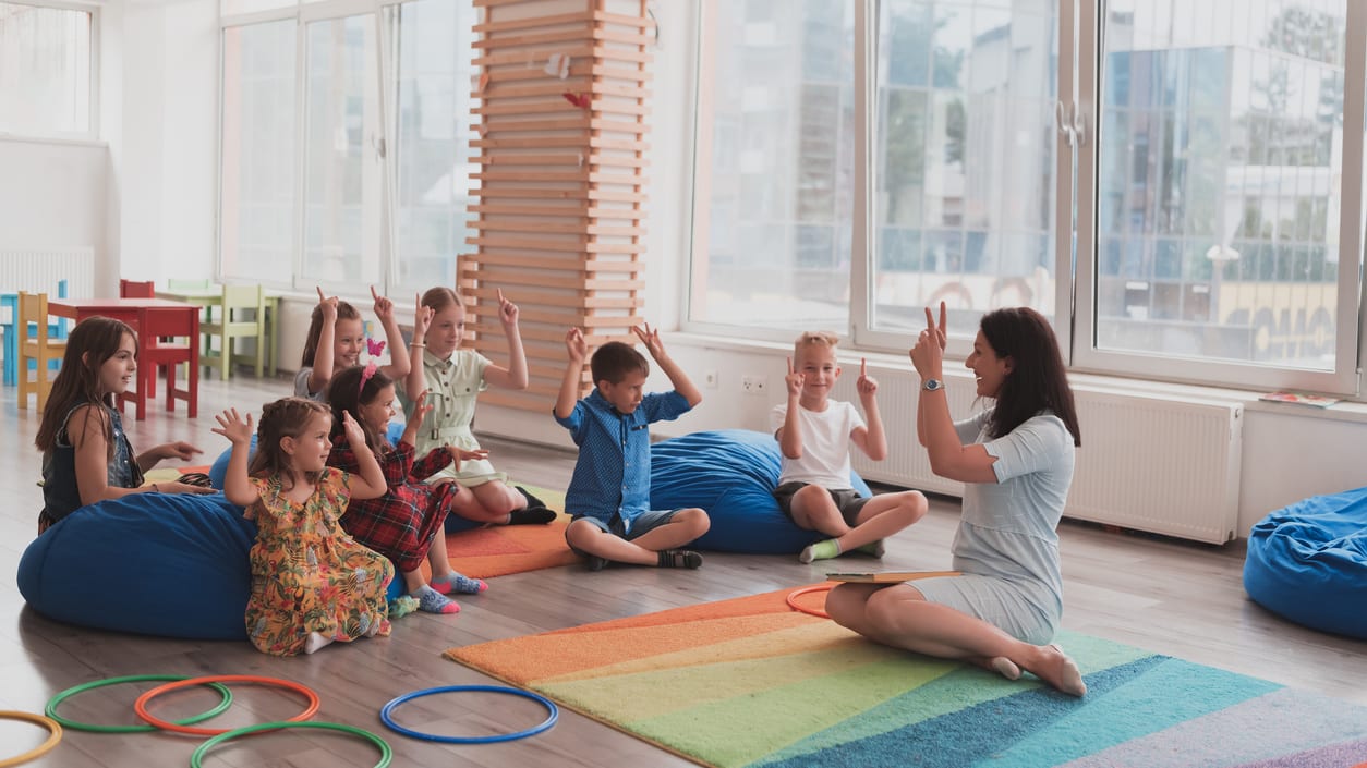 A group of children sitting on bean bags in a classroom.