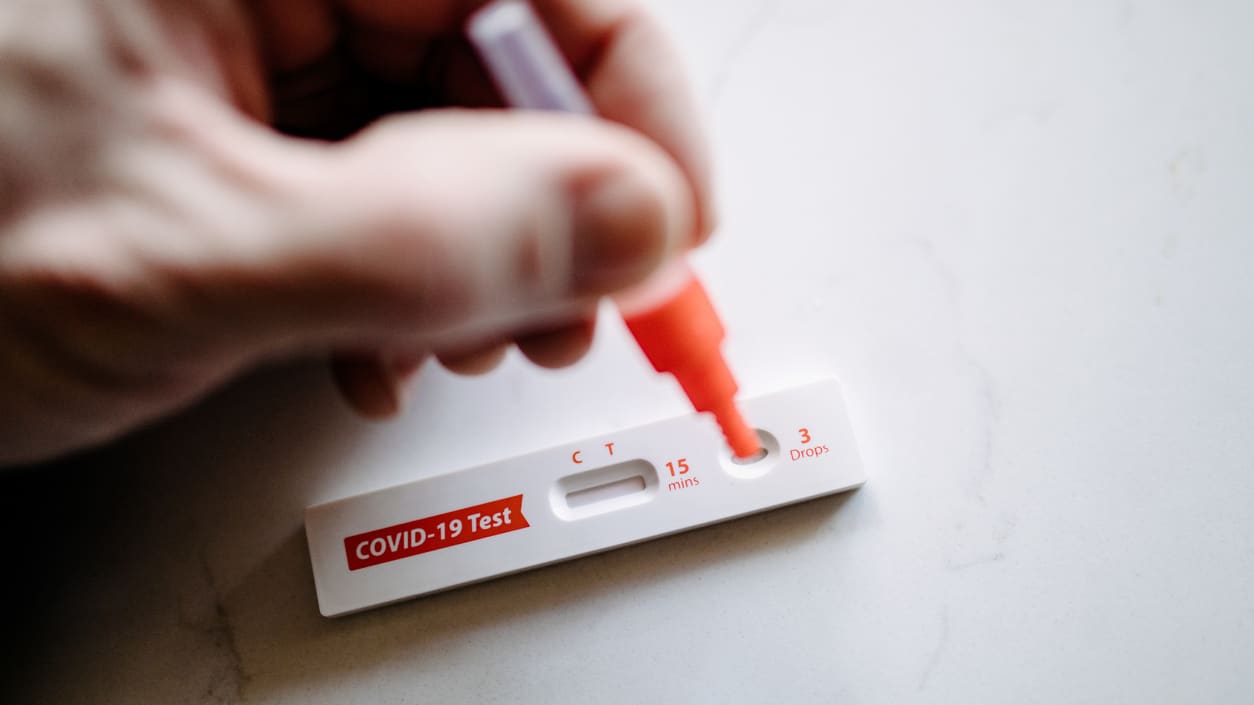 A person holding a blood test on a white table.