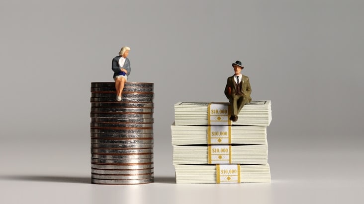 Miniature business people sitting on top of stacks of money.