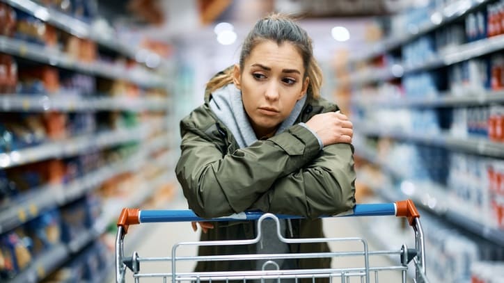 A woman sitting in a shopping cart in a supermarket.