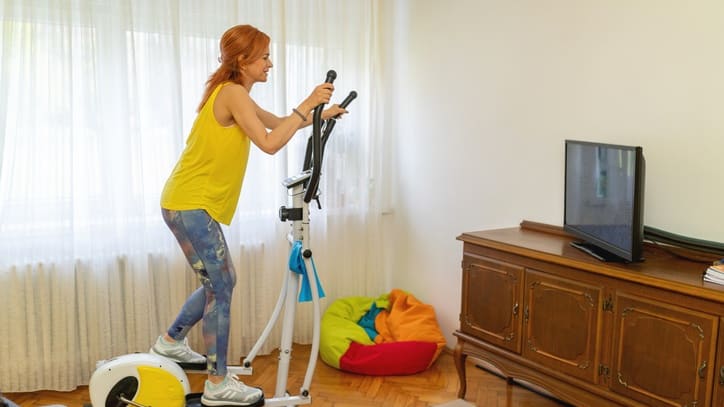 A woman on an exercise bike in a living room.