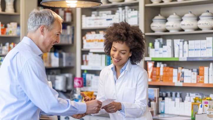 A pharmacist handing over a prescription to a customer in a pharmacy.