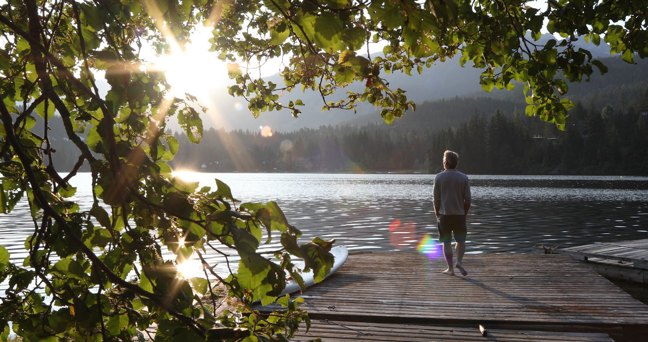 Man on dock overlooking lake at sunrise