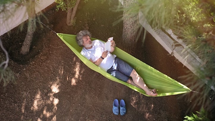 A man in a hammock reading a book.