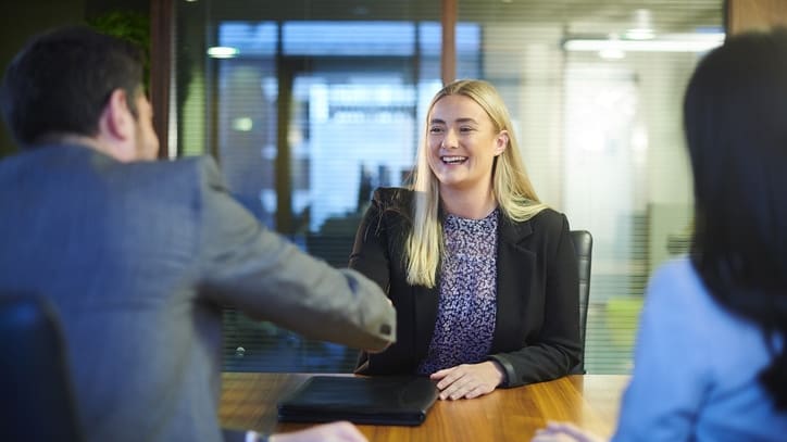 A business woman shaking hands with a man in an office.