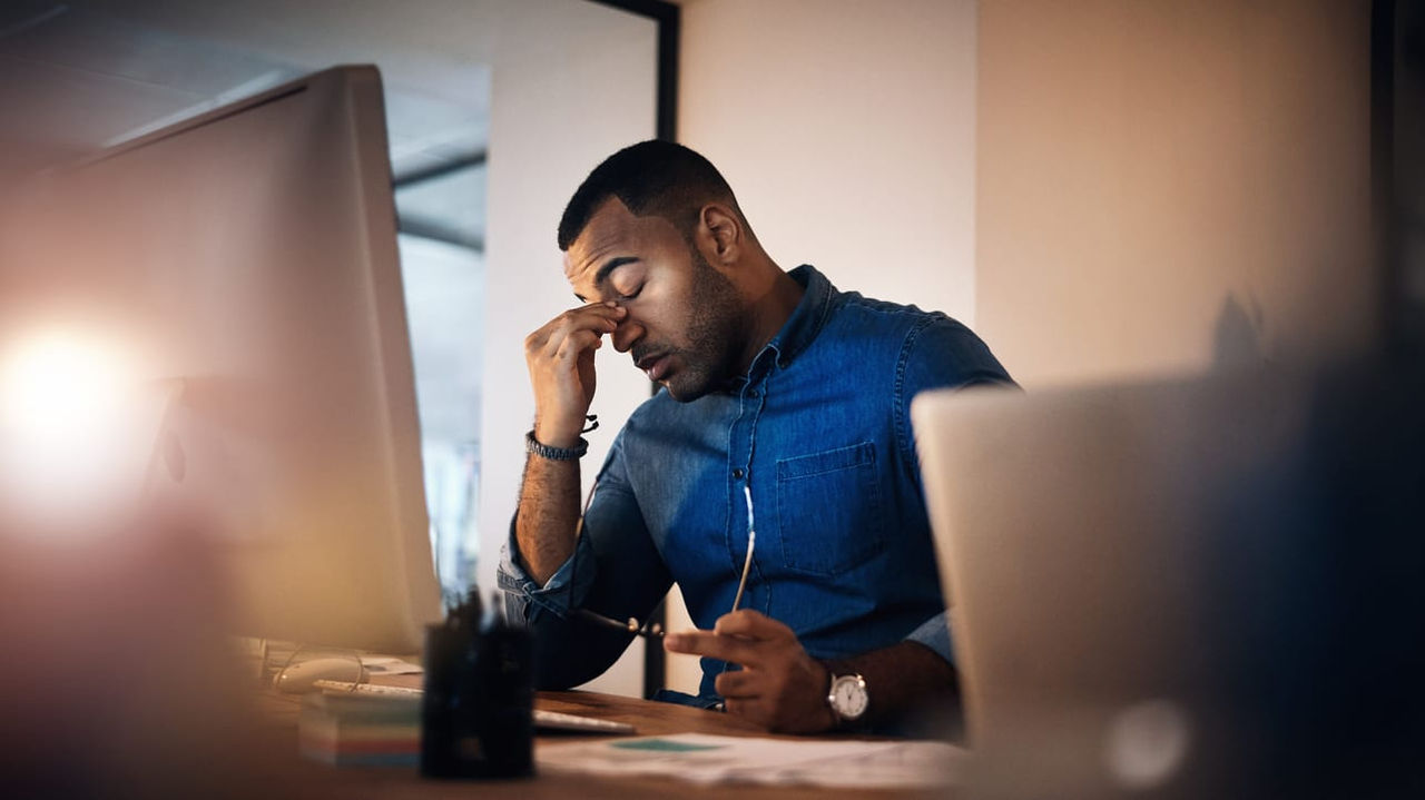 A man is sitting in front of a computer with his head in his hands.