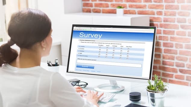 A woman is using a computer to fill out a survey.