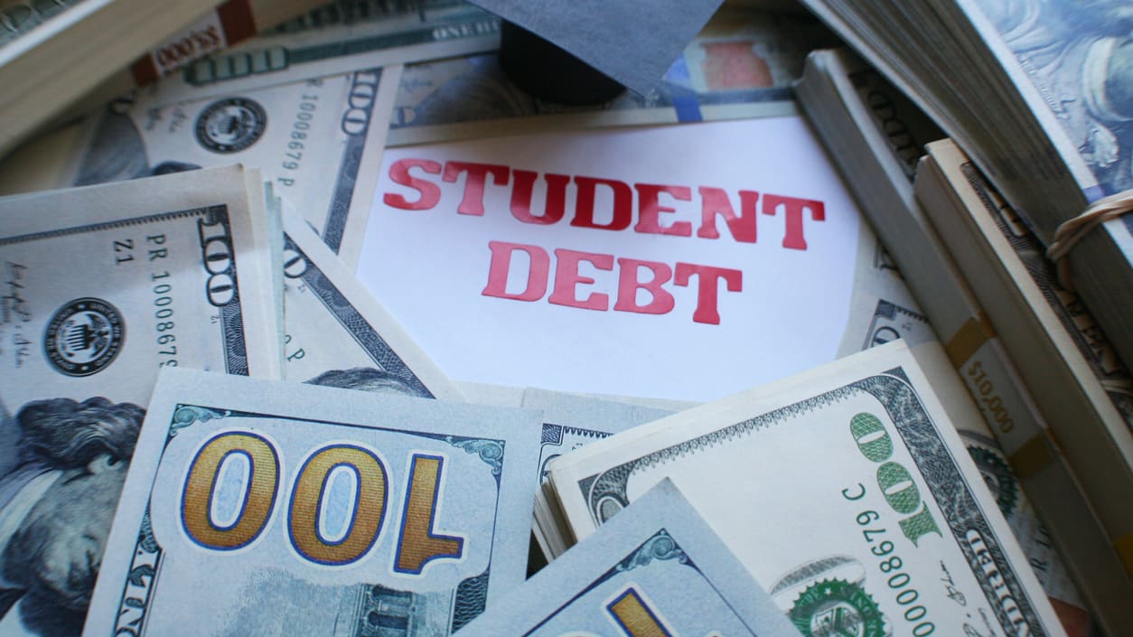 A pile of money with the words student debt on it.