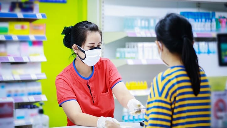 A woman wearing a face mask at a pharmacy.