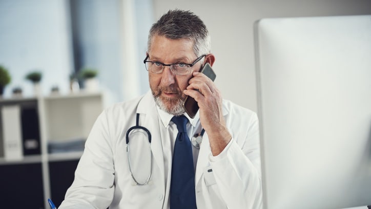 A doctor talking on the phone at his desk.