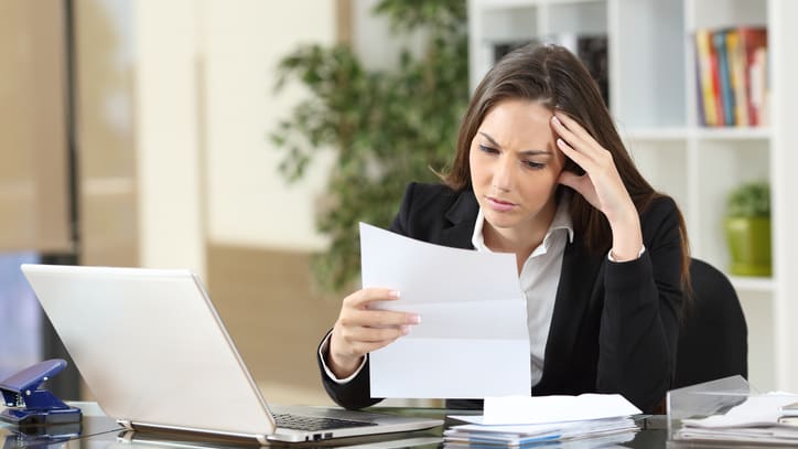 A woman in a business suit is looking at a piece of paper.