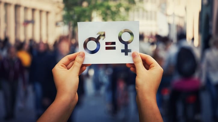 A person holding up a paper with a male and female symbol on it.