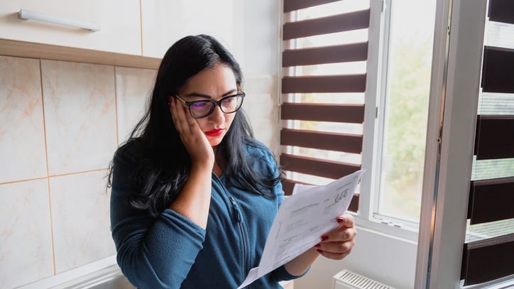 A woman looking at a paper in front of a window.