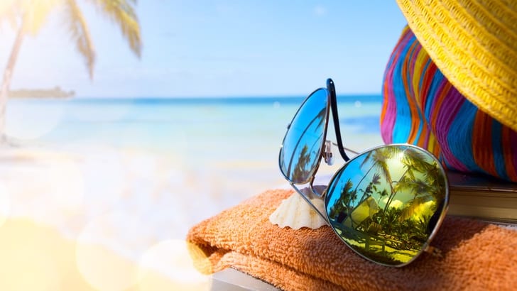 Sunglasses on a towel on a beach.
