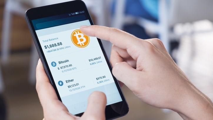 A person holding a smartphone with bitcoin on the screen.
