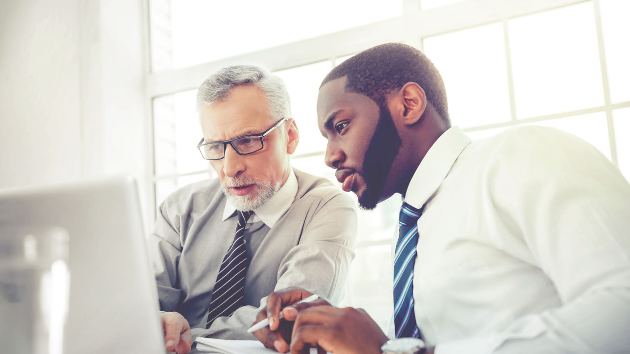 Two businessmen working together on a laptop.