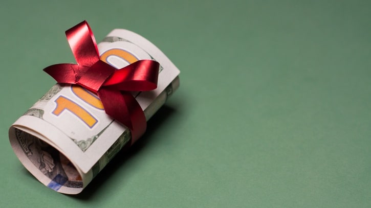 A roll of money with a red bow on a green background.